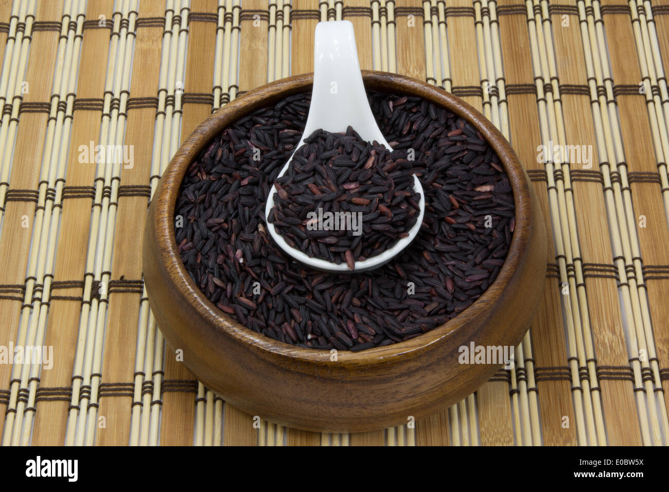 Schwarzer Reis in Holz Schlag und Keramik Löffel mit Bierdeckel Stockfoto
