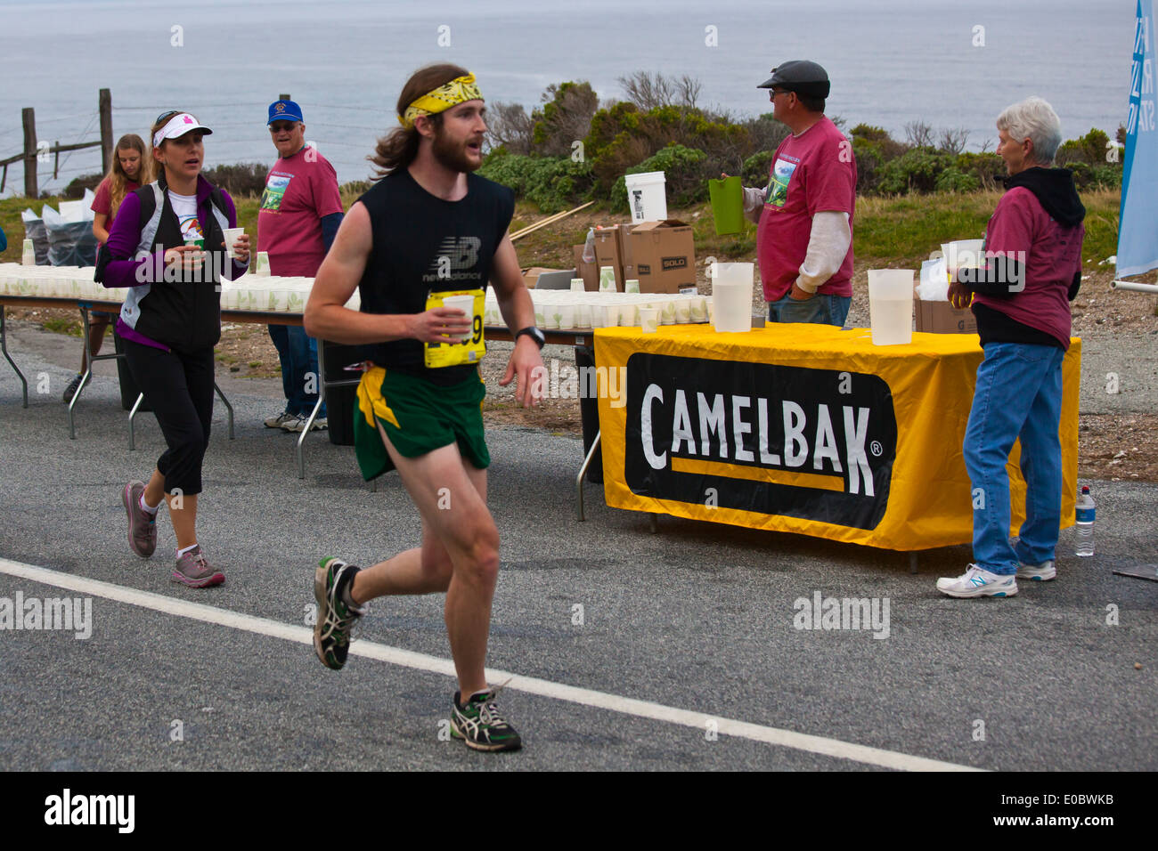 Läufer sind Erfrischungen gesponsert von Camelback auf dem Highway 1 während der 2014 Big Sur Marathon - BIG SUR, Kalifornien angeboten. Stockfoto