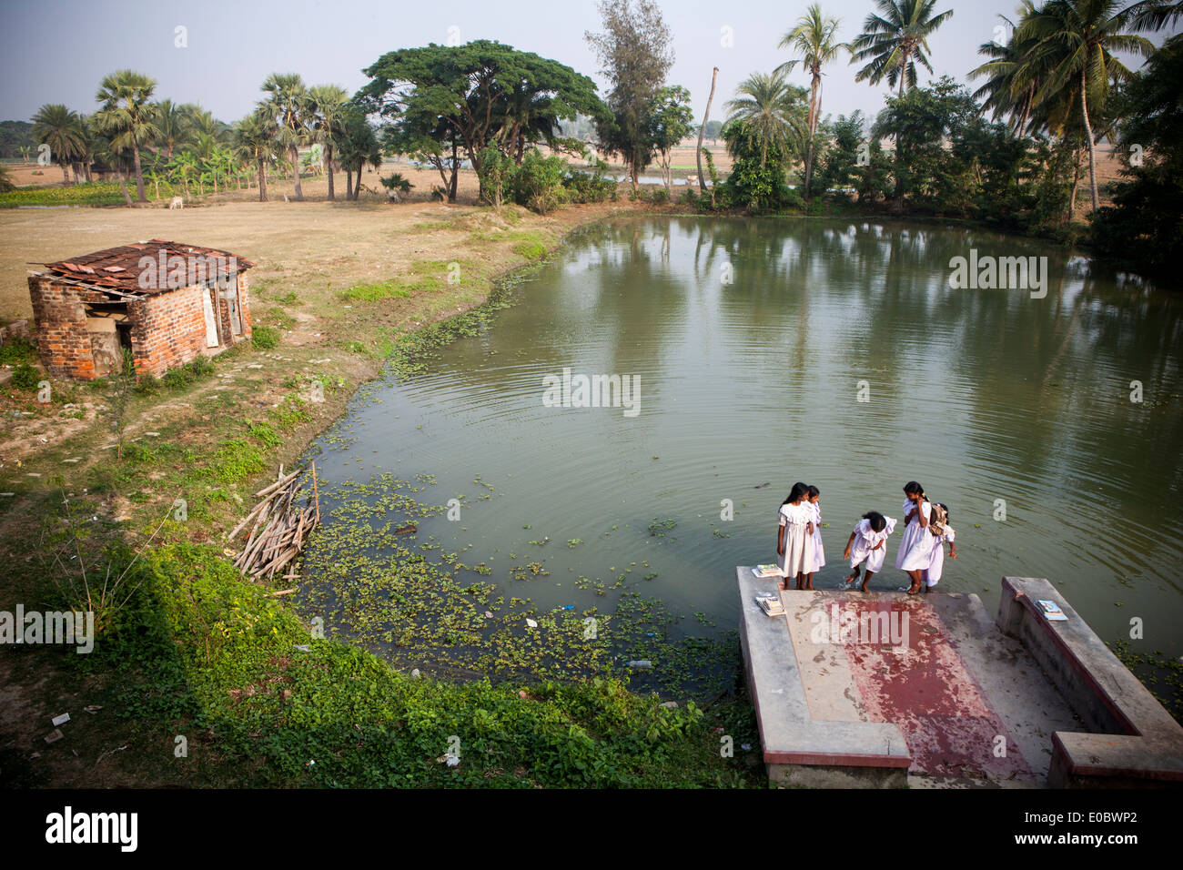 Indische Schulmädchen waschen Sie ihre Füße neben einem Teich Stockfoto
