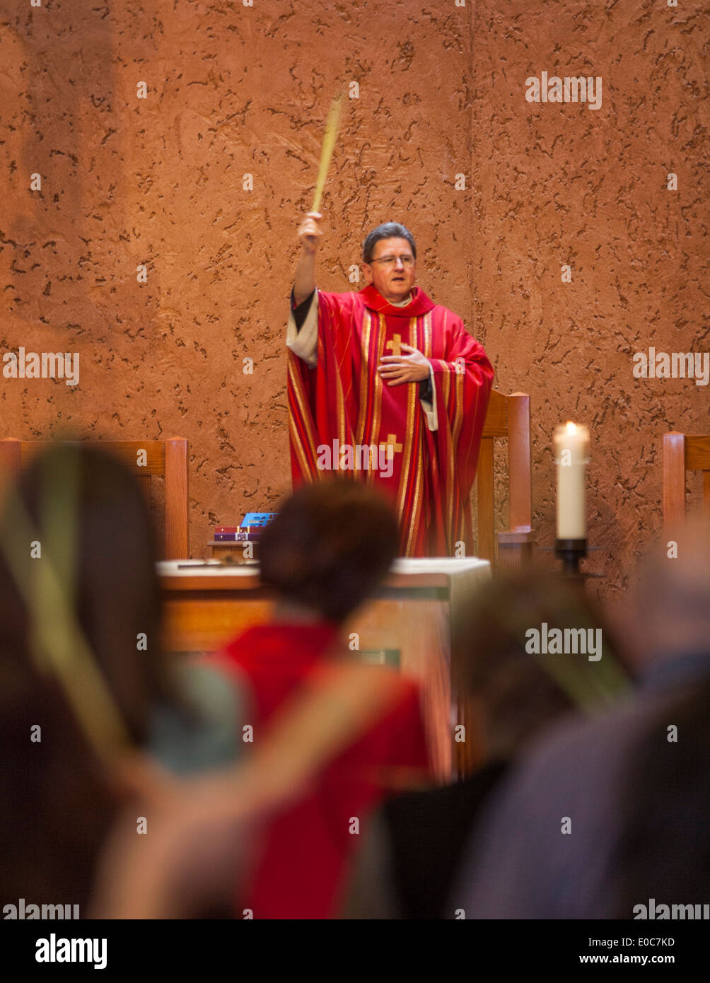 Die Pfarrer von St. Timothy katholische Kirche, Laguna Niguel, CA, winkt einem Palmwedel wie seine Gemeinde für Palmsonntag Masse sammelt. Hinweis rot Gewand. Stockfoto