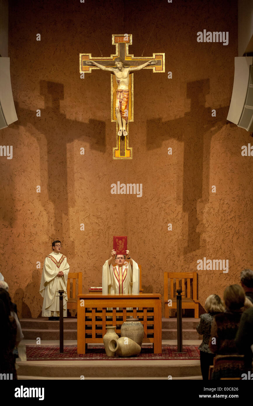 Die vietnamesische Assistent Pastor (links) Uhren als seinem Pfarrer wirft das Evangelium während einer Messe in der katholischen Kirche St. Timothy, Laguna Niguel, CA. Stockfoto