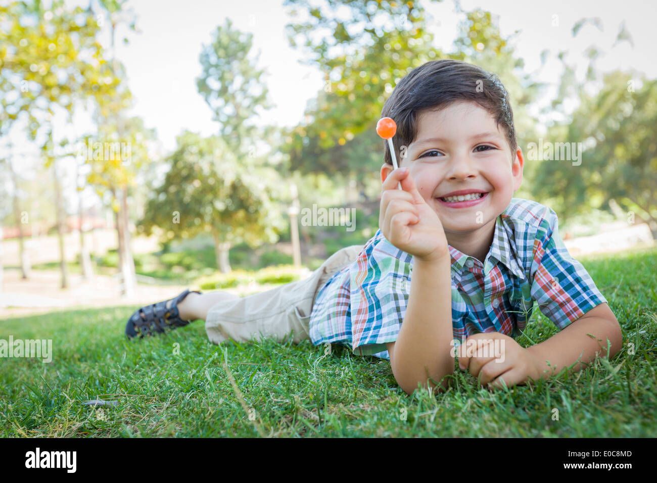 Hübscher Junge seine Lollipop im Freien auf dem Rasen genießen. Stockfoto