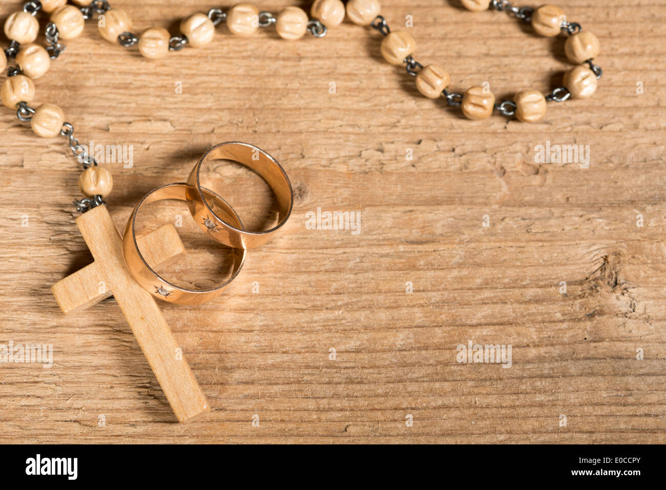 Weding Ringe und Rosenkranz auf dem alten Schreibtisch aus Holz Stockfoto