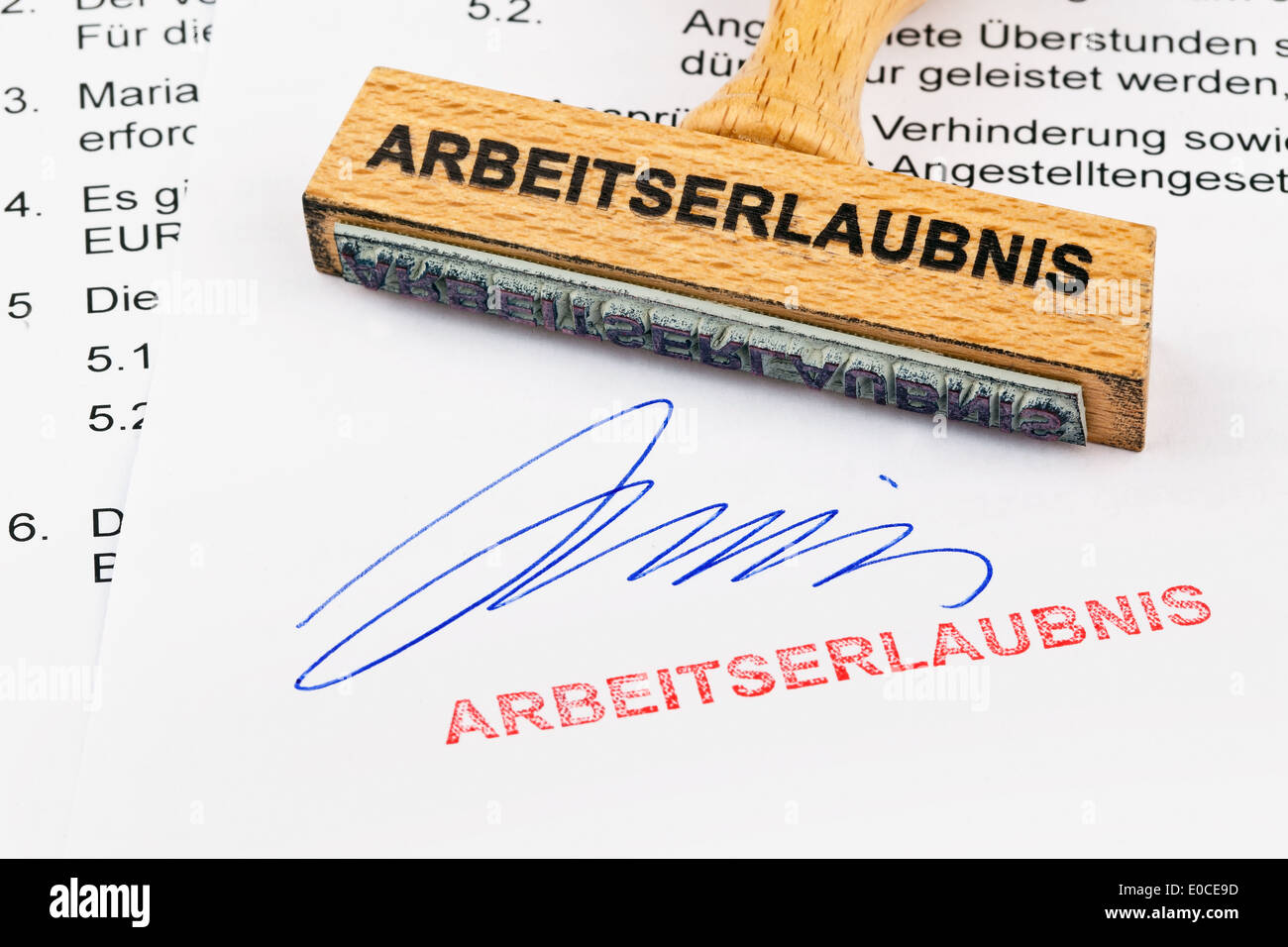 Eine Briefmarke aus Holz liegt an einem Dokument. Label Arbeitserlaubnis, Ein Stempel aus Holz Liegt Auf Einem Linksklick. Aufschrift Arbeitserlaubni Stockfoto