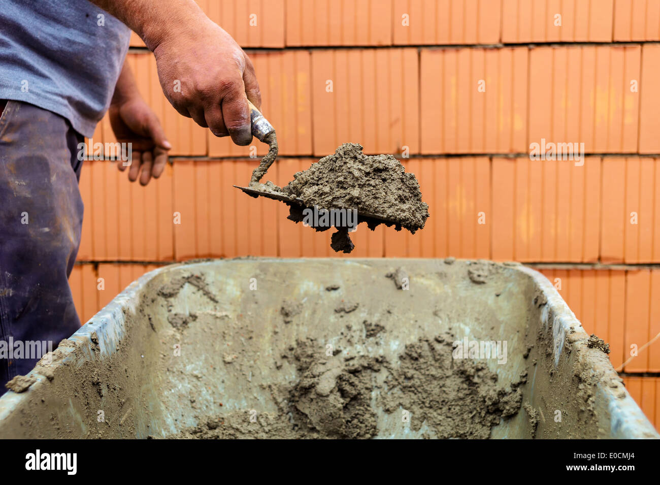 Bauarbeiter mit Kelle mit der Wand einer Muschel in Massivbauweise Stockfoto