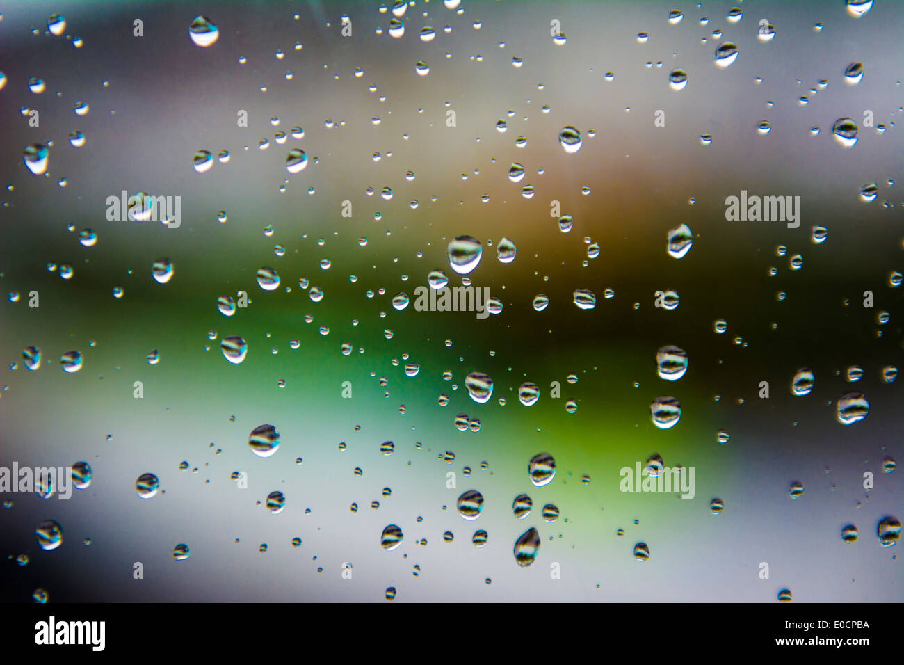 Regenwasser-Tropfen auf ein Glas-Fenster-Schmerz mit dem Hintergrund unscharf. Stockfoto