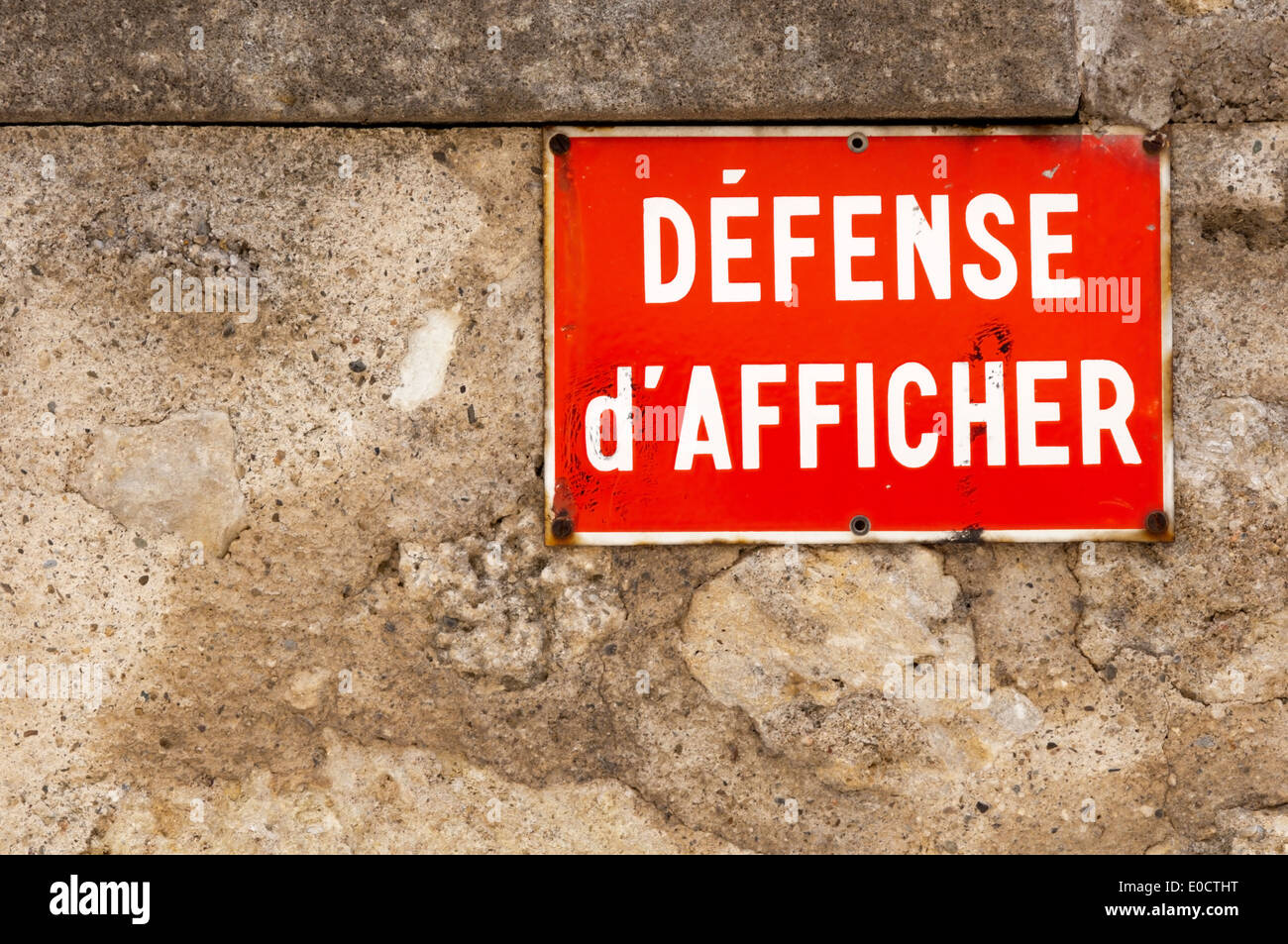 Eine französische Défense d'Afficher Blechschild befestigt an einer Steinmauer. Stockfoto