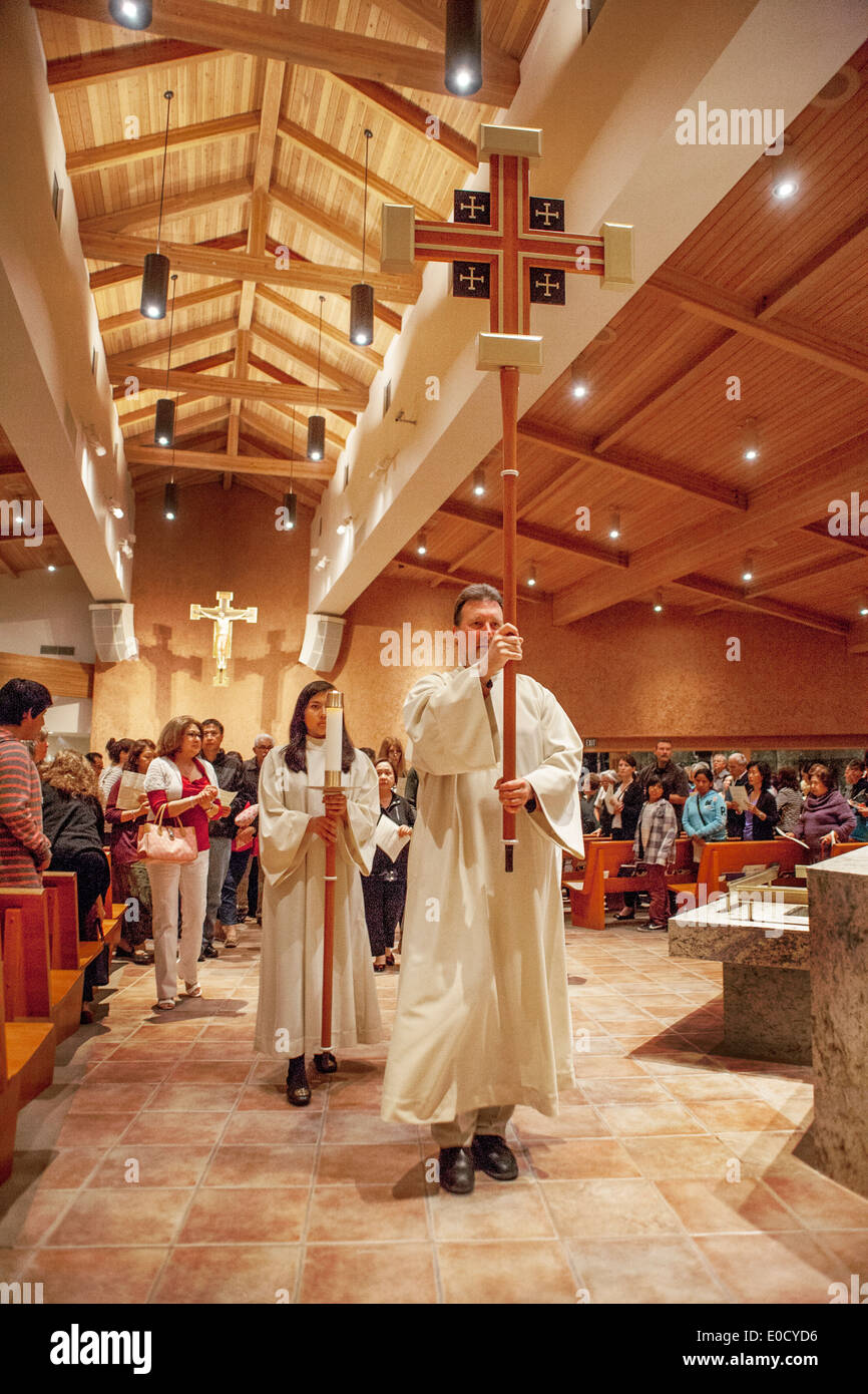 Die Gemeinde beobachtet, wie Roben Altar Server tragen Kerzen und ein Kreuz wie sie eine Prozession am Gründonnerstag in der St. Timothy katholische Kirche, Laguna Niguel, CA führen. Stockfoto