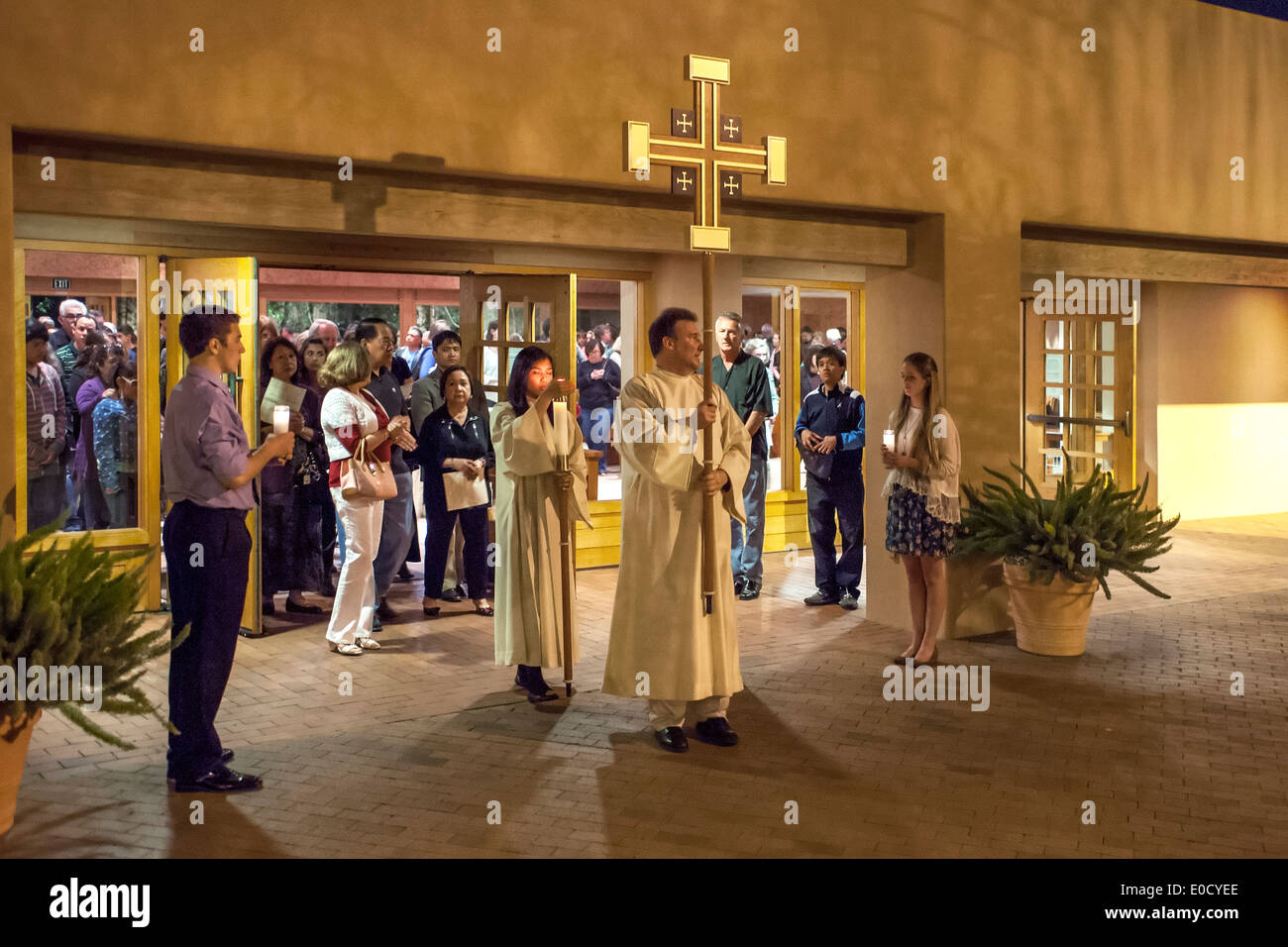 Die Gemeinde beobachtet, wie Roben Altar Server tragen Kerzen und ein Kreuz wie sie eine Prozession am Gründonnerstag in der St. Timothy katholische Kirche, Laguna Niguel, CA führen. Stockfoto