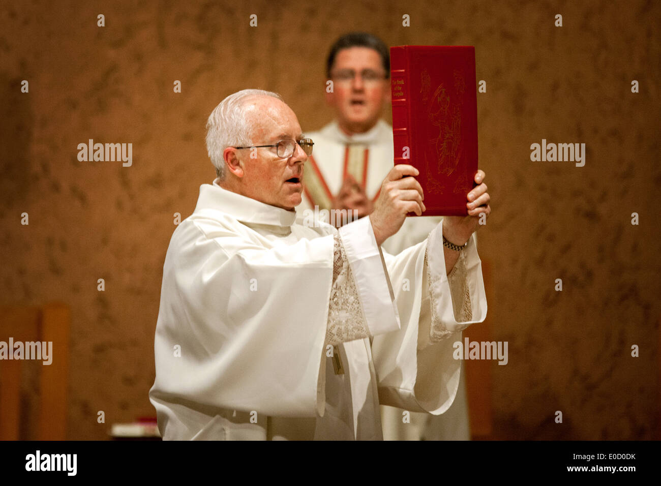 Eine ältere Diakon hält das Evangelium während der großen Osternacht-Messe in St. Timothy katholische Kirche, Laguna Niguel, CA. Hinweis Pastor im Hintergrund. Stockfoto