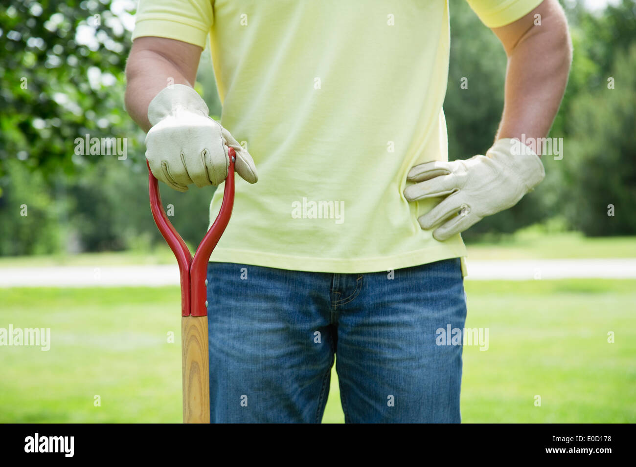 Mann mit Gartenarbeitwerkzeug im Hinterhof stehen Stockfoto