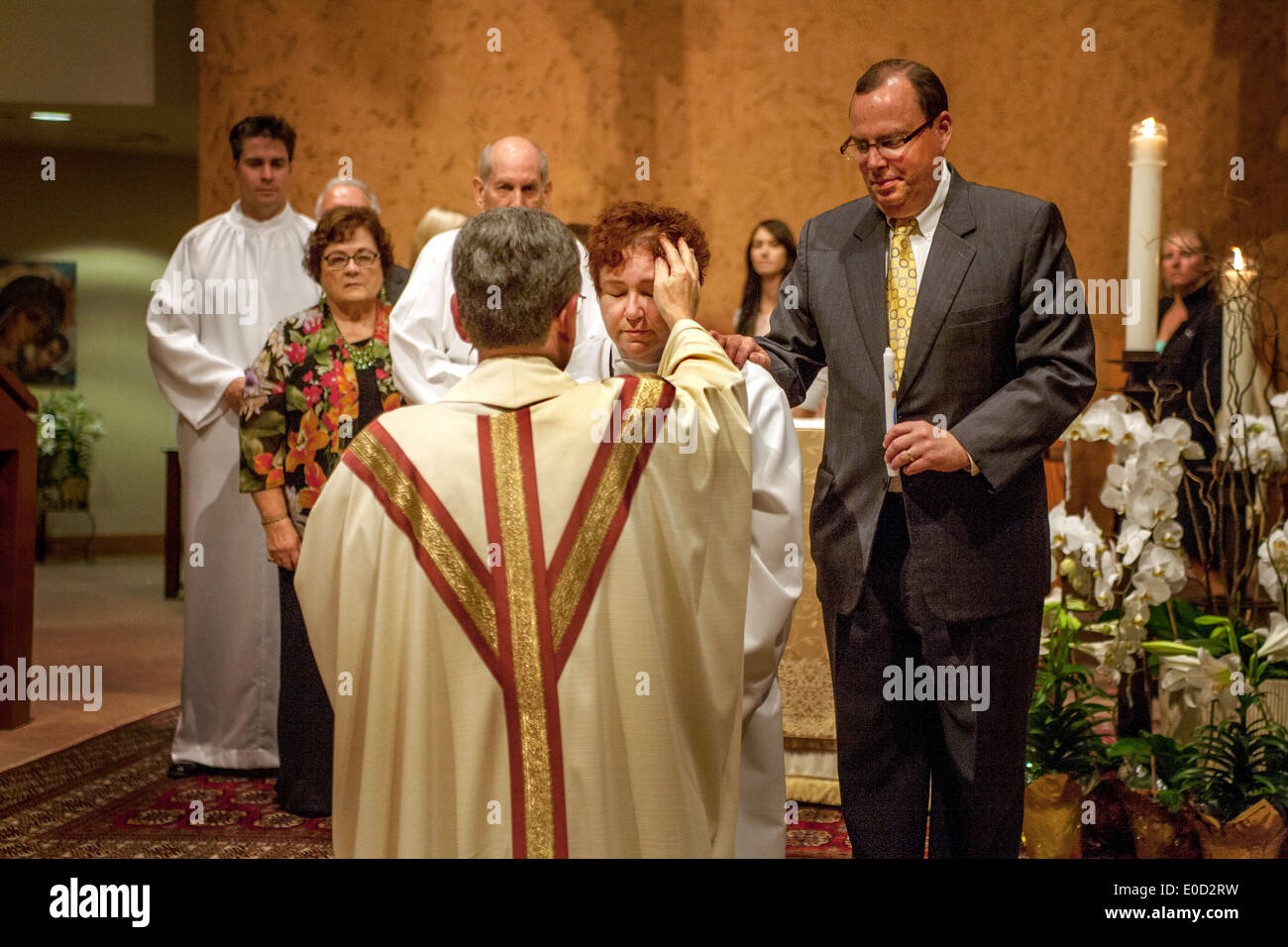 Die Pfarrer von St. Timothy katholische Kirche, Laguna Niguel, CA, segnet neue Mitglieder der Kongregation in der Nacht ihrer Taufe. Hinweis: weiße Roben und sponsor auf der rechten Seite. Stockfoto