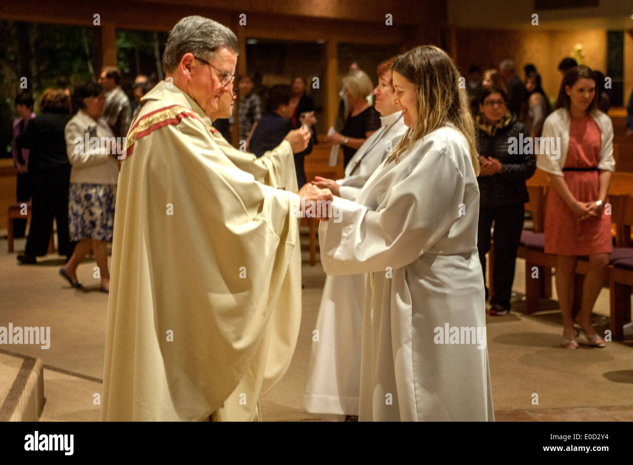 Die Pfarrer von St. Timothy katholische Kirche, Laguna Niguel, CA, bietet neue Mitglieder der Kongregation in der Nacht ihrer Taufe Kommunion. Beachten Sie die weiße Gewändern. Stockfoto