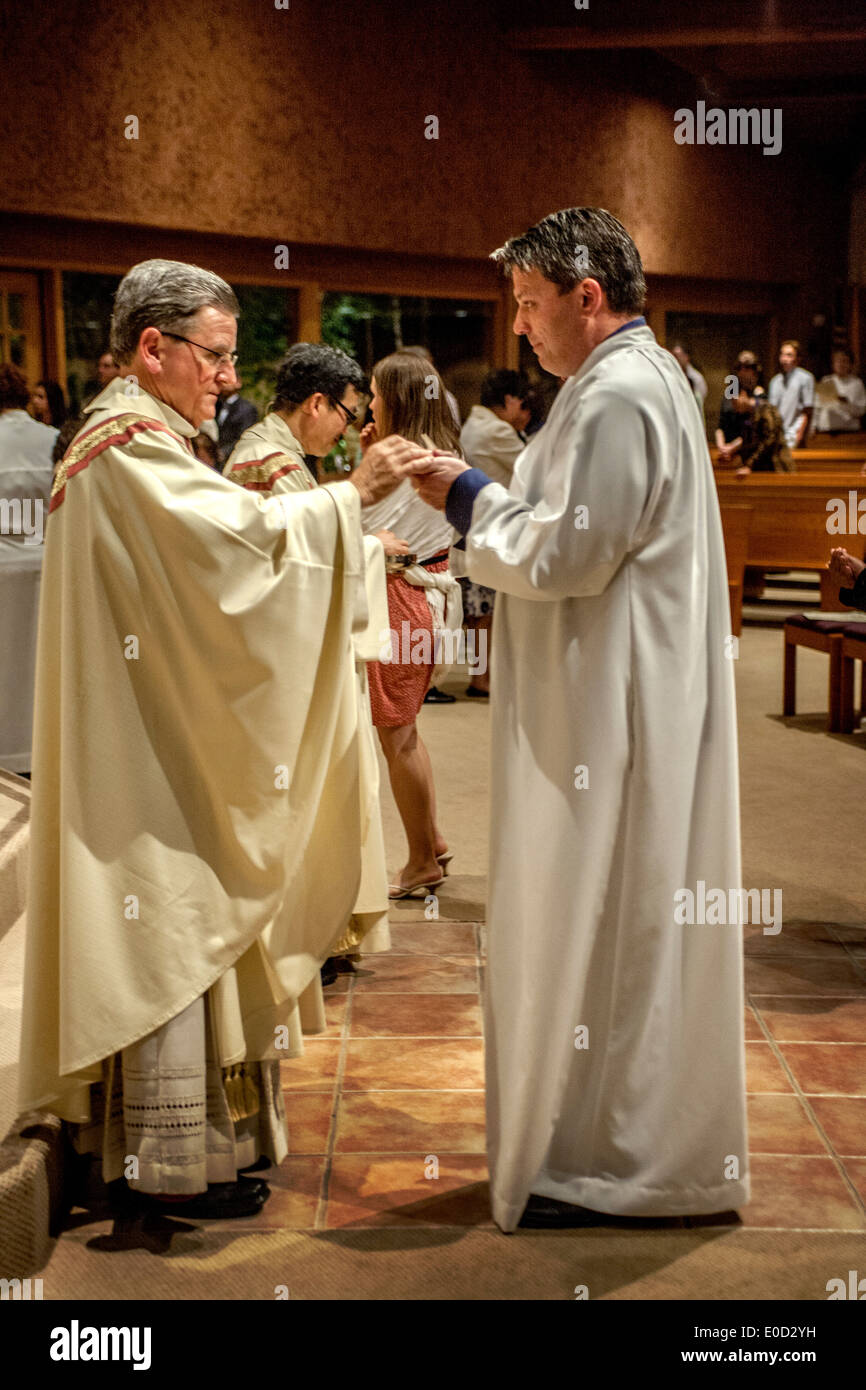 Die Pfarrer von St. Timothy katholische Kirche, Laguna Niguel, CA, bietet eine neue Mitglieder der Kongregation in der Nacht seiner Taufe Kommunion. Beachten Sie die weiße Gewändern. Stockfoto
