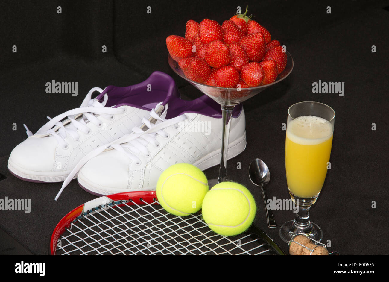 Tennisausrüstung und Erdbeeren mit einem Glas Bucks fizz Stockfoto