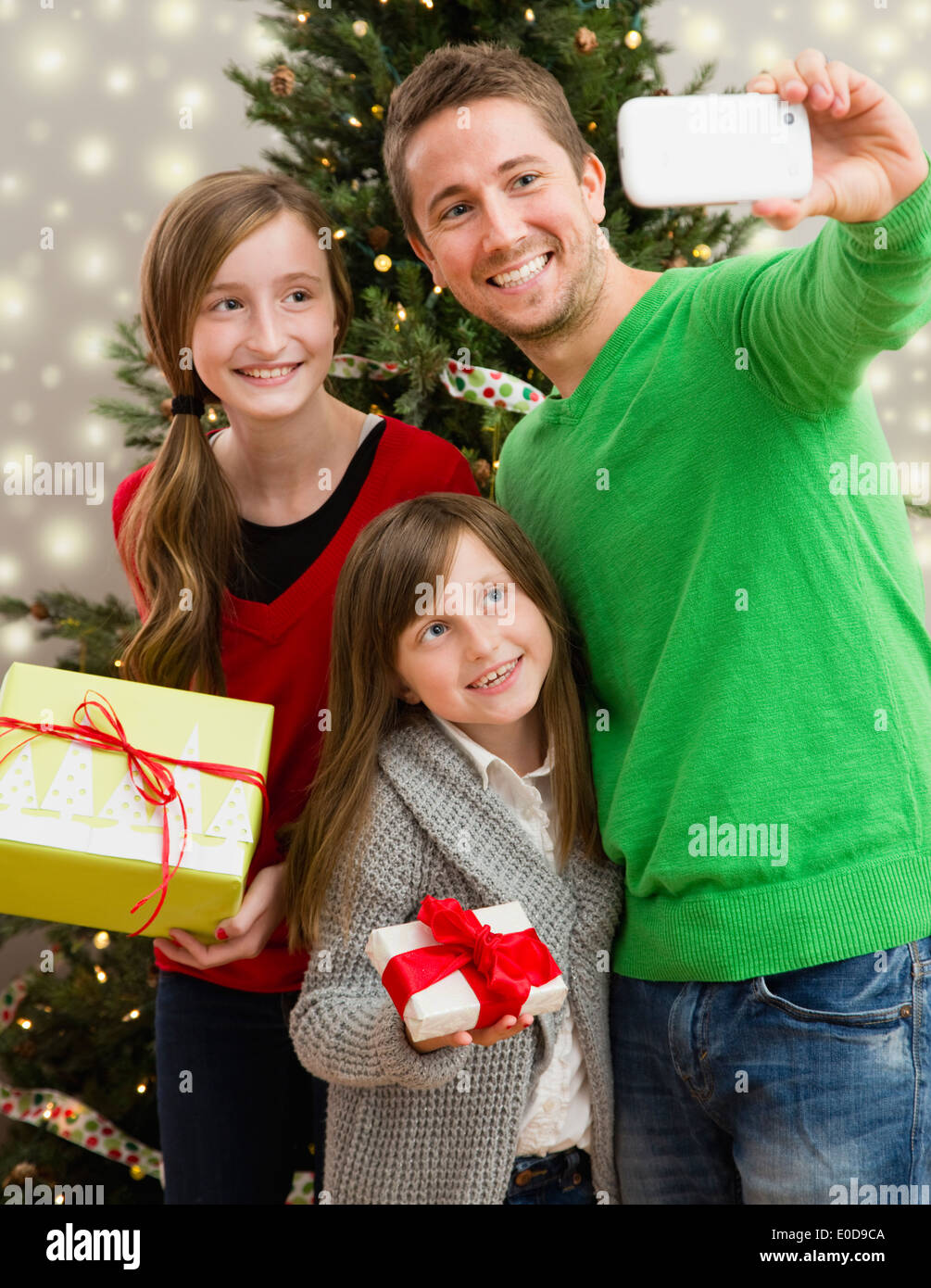 Vater mit zwei Töchtern (8-9, 10-11) fotografieren sich mit Weihnachtsgeschenken Stockfoto