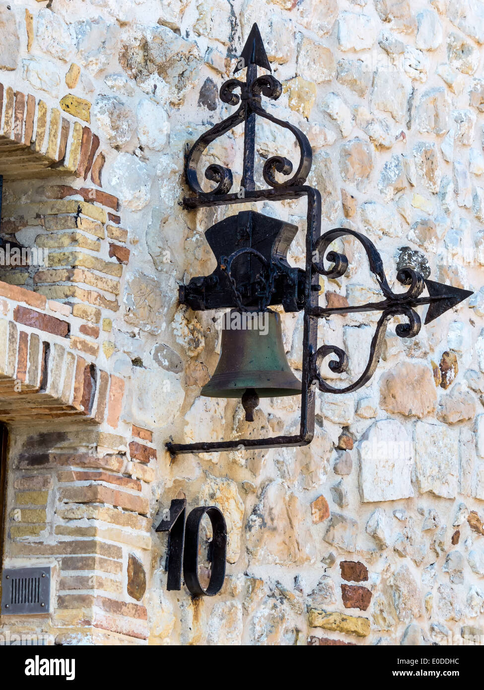 Alte Glocke von einer Hauswand eines Steinhauses, Alte Glocke ein Einer Hausmauer Eines Steinhauses Stockfoto