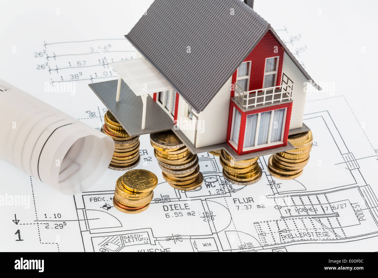 Ein Wohnhaus steht auf monetäre Münzen und ein Architekt Plan. Symbolische Foto für Bau sparen, Ein Wohnhaus Steht au Stockfoto