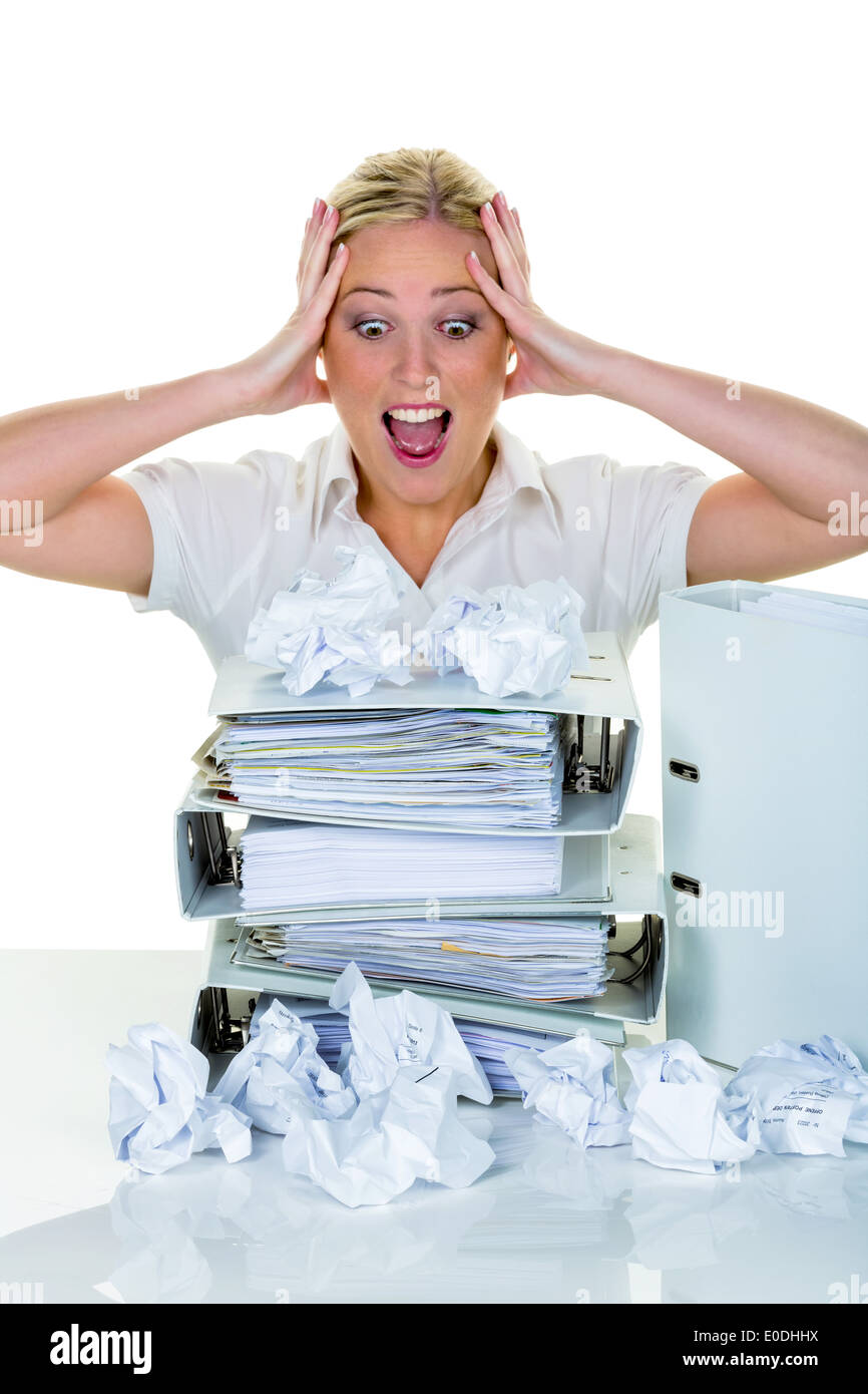 Eine junge Frau verzweifelt im Büro zwischen vielen Dateien und zerknüllte Papier. Symbolische Foto für Stress, Burnout und Nacharbeiten. Stockfoto