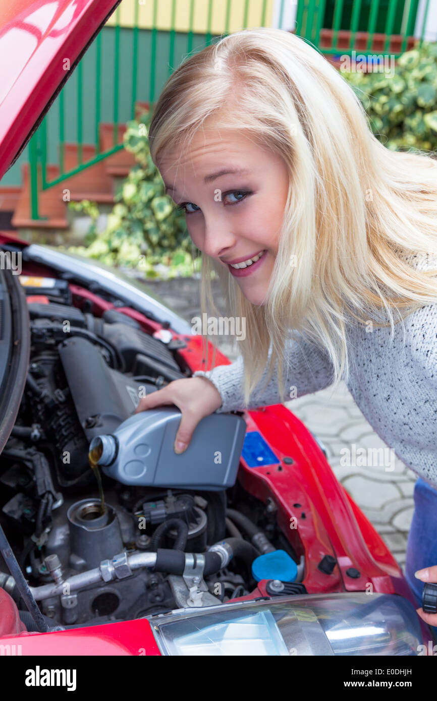Eine junge Frau füllt Öl in ihrem Auto. Sicher reisen mit dem richtigen Druck, Eine Junge Frau Fuellt ÷l in Dachmarke Auto Nach. Sicher Stockfoto