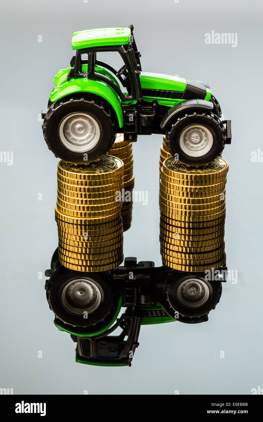 Bauern in der Landwirtschaft müssen mit steigenden Kosten rechnen. Höhere Preise mit Futtermittel, Dünger und Pflanzen. Traktor mit Münzen, Ba Stockfoto