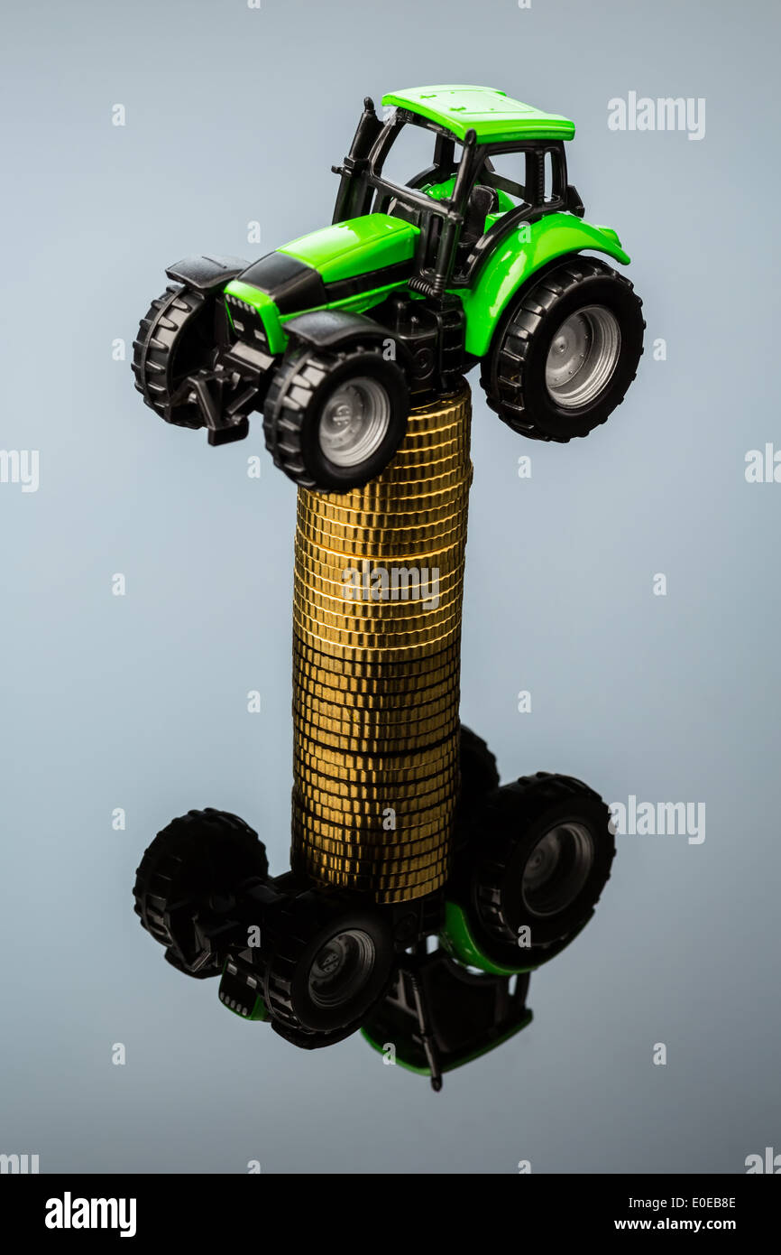 Bauern in der Landwirtschaft müssen mit steigenden Kosten rechnen. Höhere Preise mit Futtermittel, Dünger und Pflanzen. Traktor mit Münzen, Ba Stockfoto