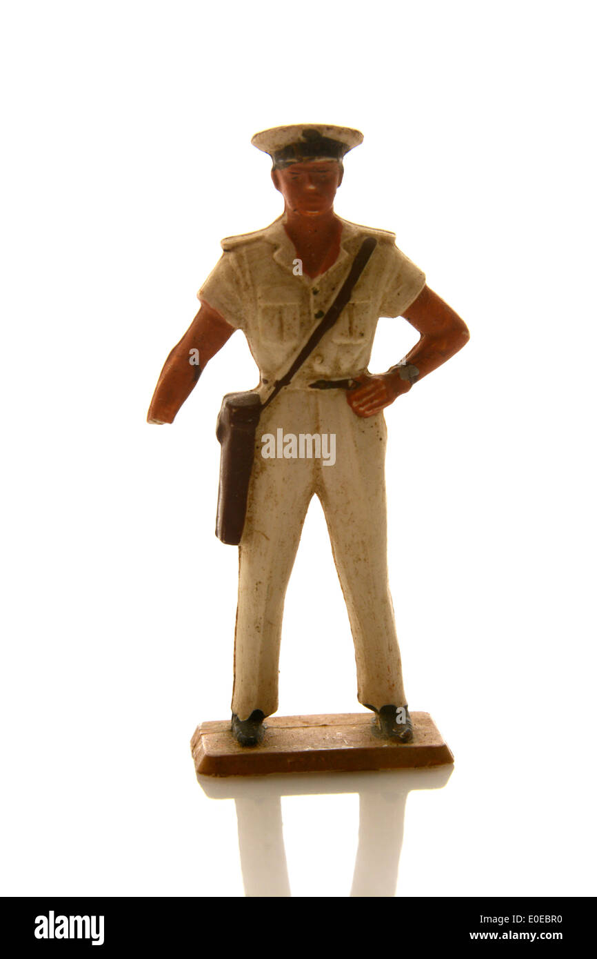 Die Soldatenfigur aus Vintage-Spielzeug in Marineuniform steht auf einer reflektierenden Oberfläche vor weißem Hintergrund Stockfoto