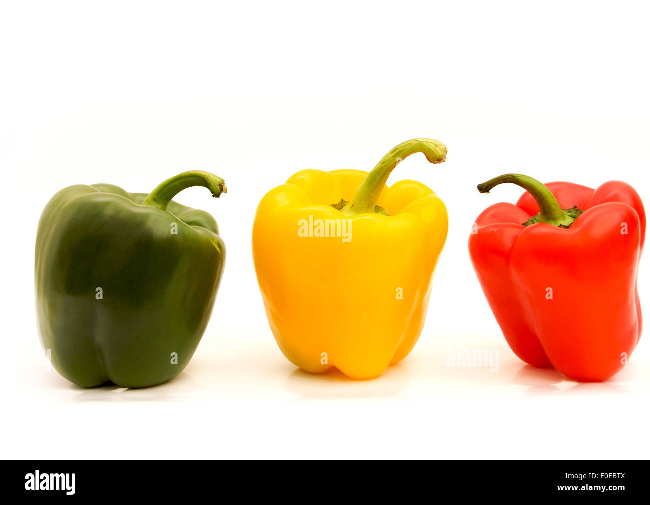 Nahaufnahme der leuchtenden gelben, roten und grünen Paprika, die wunderschön auf weißem Hintergrund angeordnet sind, um kulinarische Inspirationen zu erhalten Stockfoto