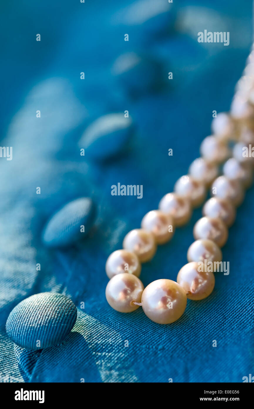 Perlenkette auf Türkis farbigen Bluse mit Knöpfen liegen Stockfoto