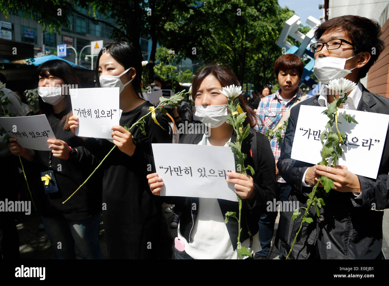 Seoul, Südkorea. 10. Mai 2014. Menschen halten Schilder und Blumen während ihrer "bleiben immer noch" stillen Marsch gegen das, was sie darauf bestehen, lax Reaktion des President Park Geun-hyes Regierung nach der Fähre eingesunken war Sewol aus der südwestlichen Insel Jindo am 16. April 2014, auf der Straße, Seoul, Südkorea, am Samstag, 10. Mai 2014 Gewässer. Zeichen zu lesen, "Stillhalten", Kapitän der Sewol pasquinading, wurde, die eine Nachricht für die Fahrgäste bis auf weiteres warten, wenn die Fähre, nach den örtlichen Medien sank Rundfunk. Stockfoto