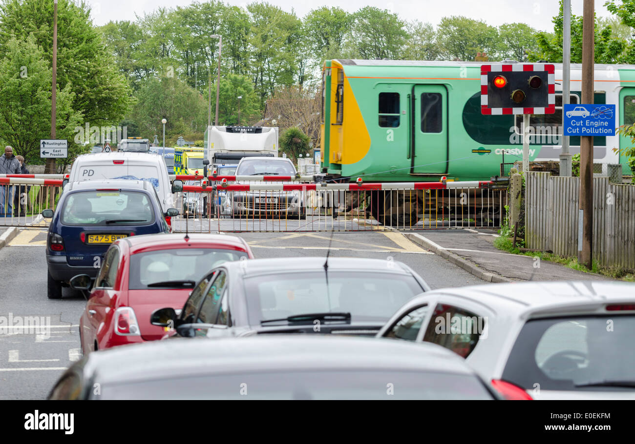 Autos an einem Bahnübergang, während eine südliche Rampe Coastway Klasse 313 Zug kreuzen in Angmering, England, UK. Stockfoto