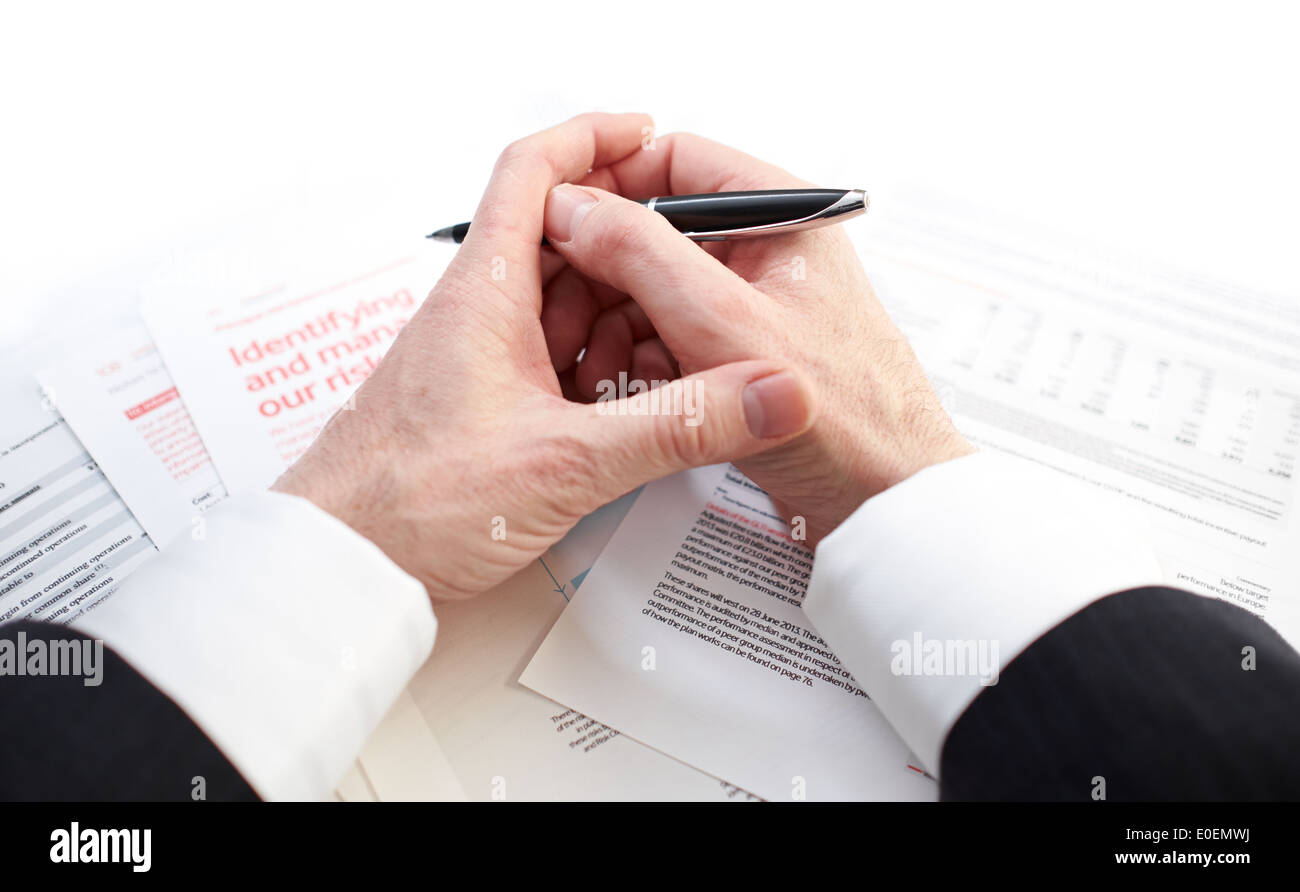 Blick hinunter auf den Händen eines Geschäftsmannes, Verträge und Risiko Management Papiere zu studieren. Stockfoto