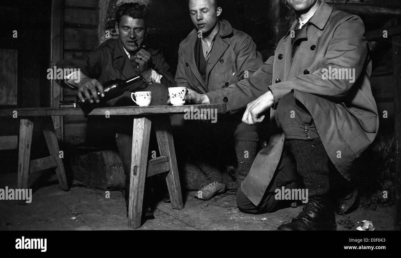 Ein Foto aus dem Jahr 1921, das eine Gruppe von Menschen zeigt, die einen geselligen Abend mit Getränken in einer Hütte in Norwegen genießen und einen Moment der Entspannung und Kameradschaft während Ostern festhalten. Stockfoto
