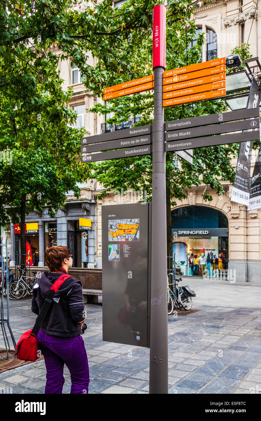 Junge weibliche Touristen schaut auf ein Zeichen zeigen Wegbeschreibungen zu Orten von Interesse in Antwerpen, in Meir, der Haupteinkaufsstraße. Stockfoto