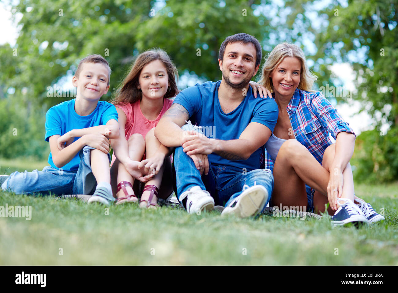 Foto der glücklichen Familie von vier sitzen auf dem Rasen im Sommer Erholung Stockfoto