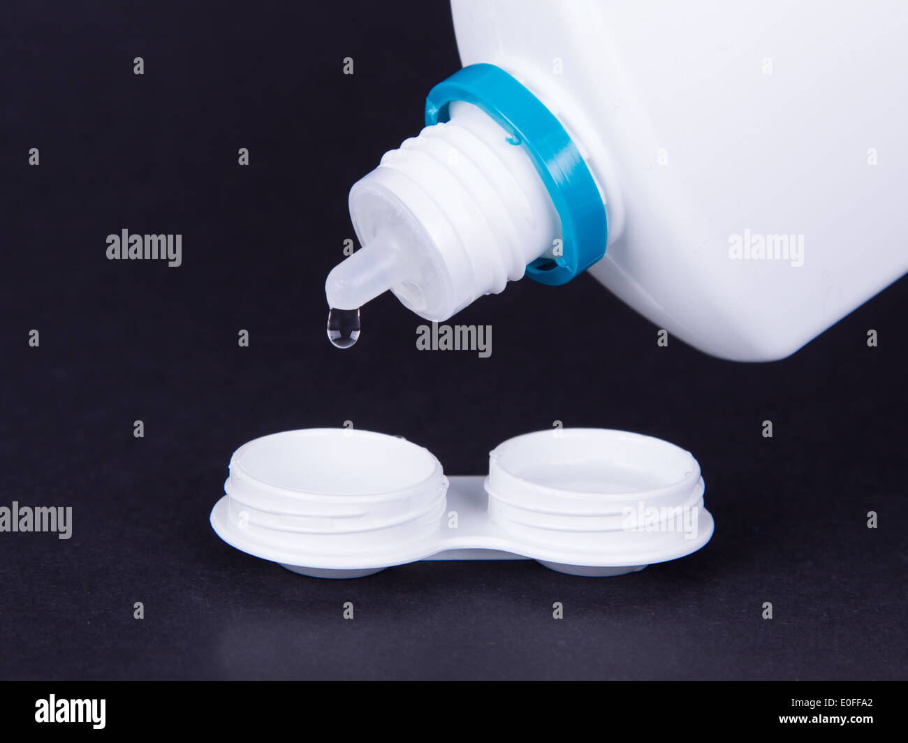 Objektiv-Gehäuse und eine Flasche Wasser isoliert auf schwarz, Kontaktlinsen Stockfoto
