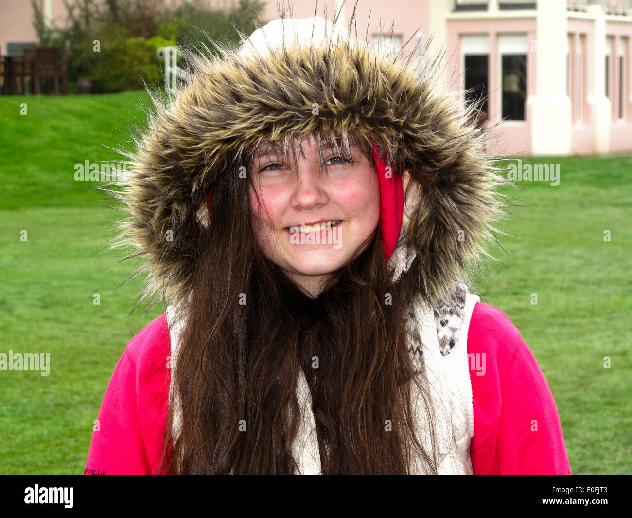 12 Jahre altes Mädchen lächelnd in die Kamera mit pelzigen Kapuze Stockfoto