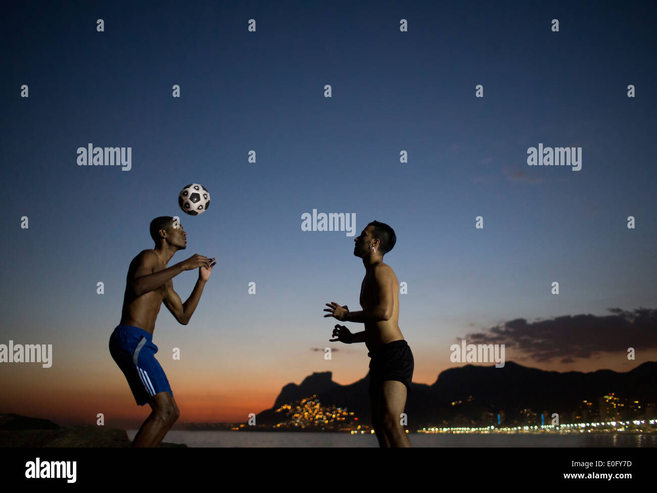 Brasilianische Männer spielen Fußball in Arpoador in Rio De Janeiro mit Ipanema im Hintergrund Stockfoto