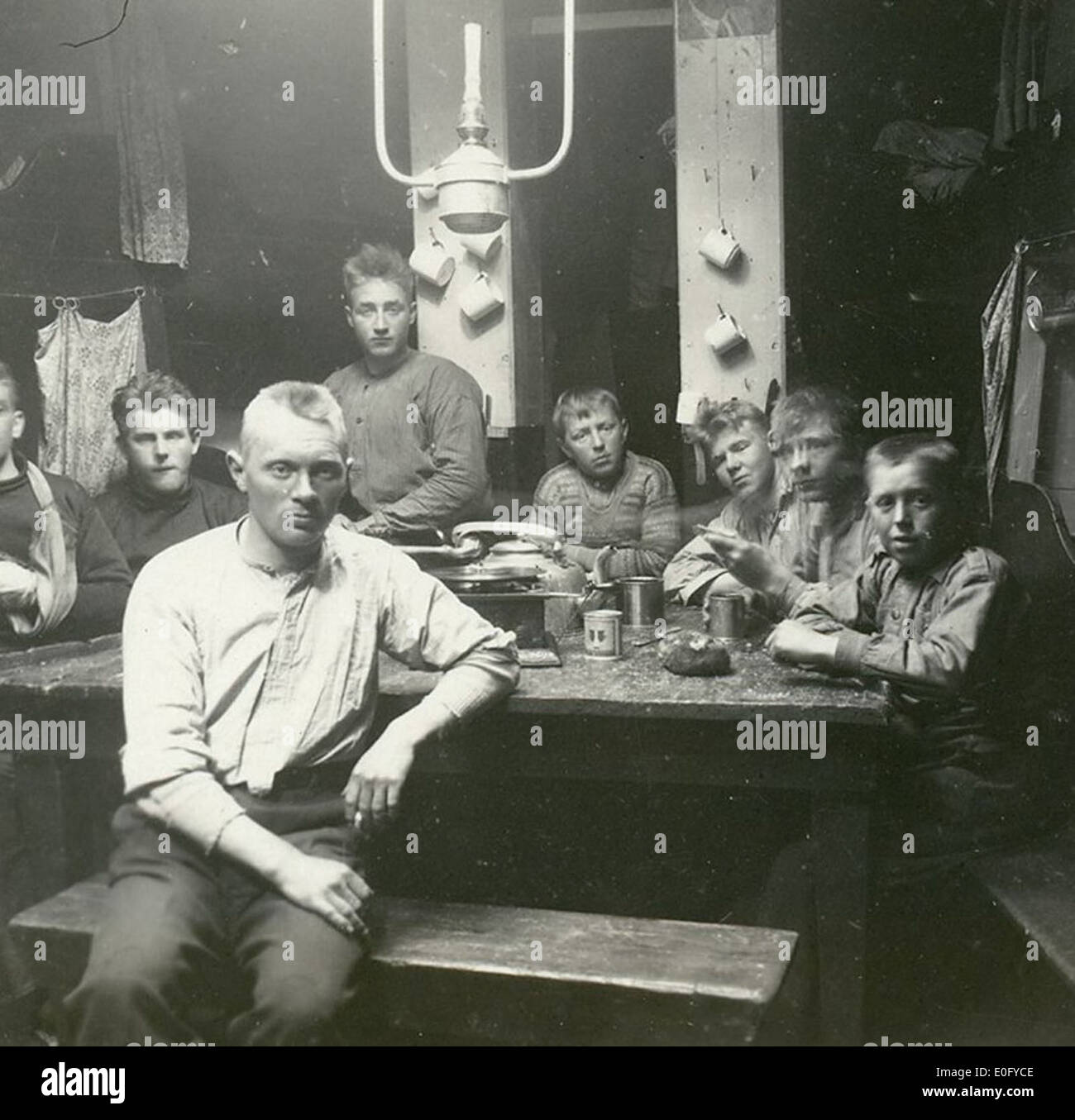 Ein Foto, das eine Gruppe von Personen, wahrscheinlich Seeleute oder Militärpersonal, zeigt, die unter rauen Bedingungen auf dem Deck eines Schiffes stehen. Das Bild zeigt eine Szene mit rauem Wetter und der Widerstandsfähigkeit der Menschen, die den Elementen gegenüberstehen. Stockfoto