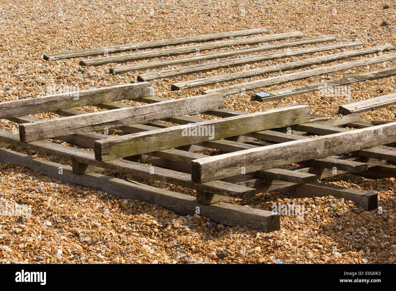 Holzlatten für die Aufbewahrung von Bootsrümpfen aus den Steinen am Strand Stockfoto