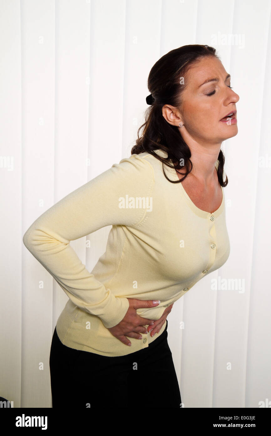 Frau mit Schmerzen im Rücken der Bandscheibe mit Büro Arbeit., Frau Mit Rueckenschmerzen der Bandscheibe Bei Bueroarbeit. Stockfoto