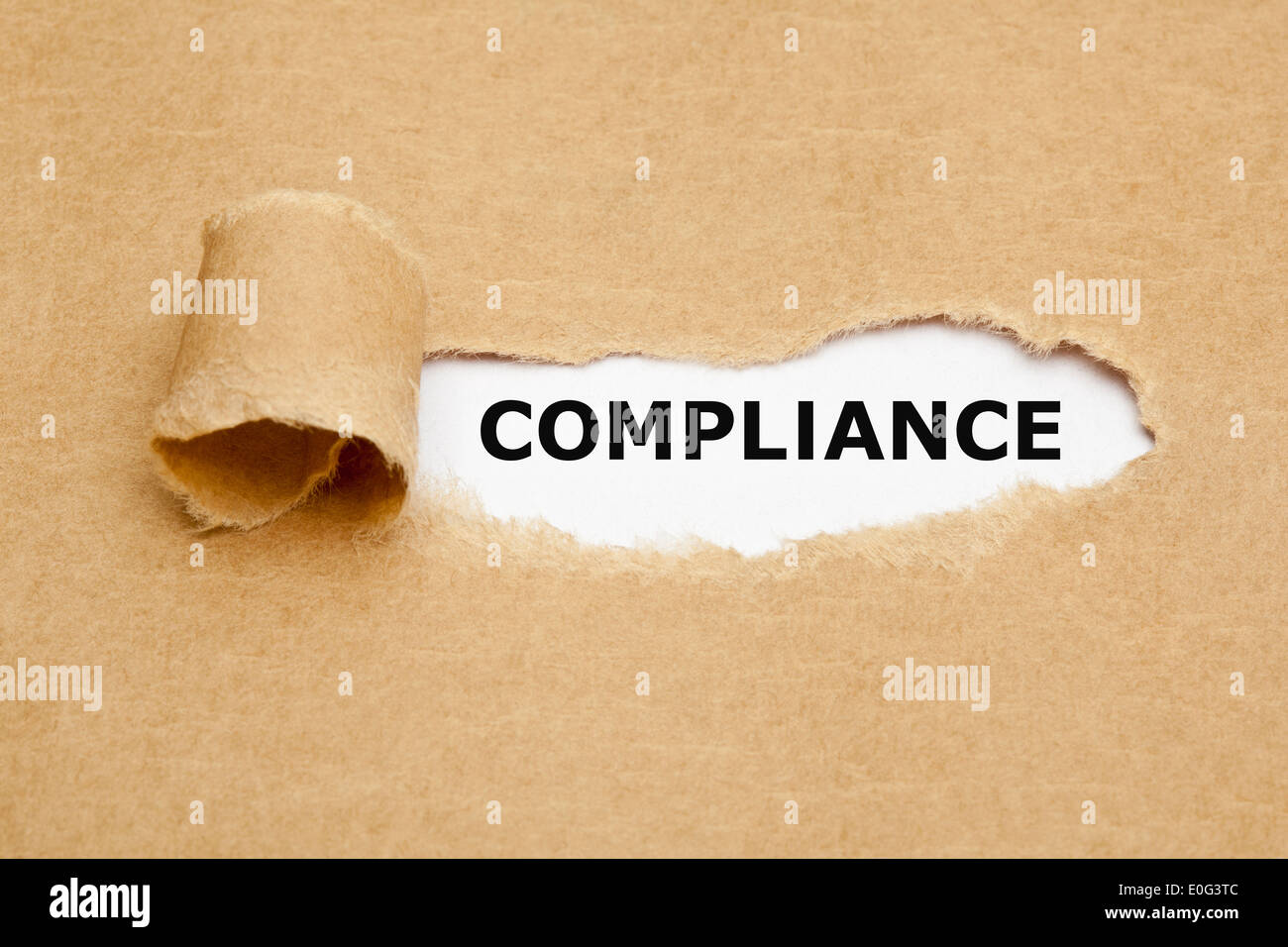 Das Wort Compliance erscheint hinter zerrissenes braunen Papier. Stockfoto