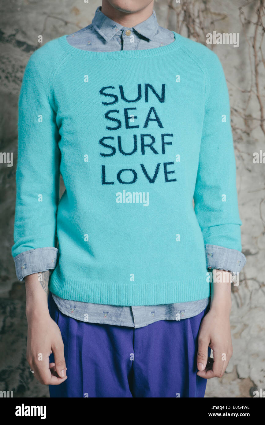 Junger Mann in einem städtischen Umfeld, träumt von Strand und wollen dorthin zu gehen, 'Sonne, Meer, Brandung, Liebe' auf dem Pullover gedruckt. Stockfoto