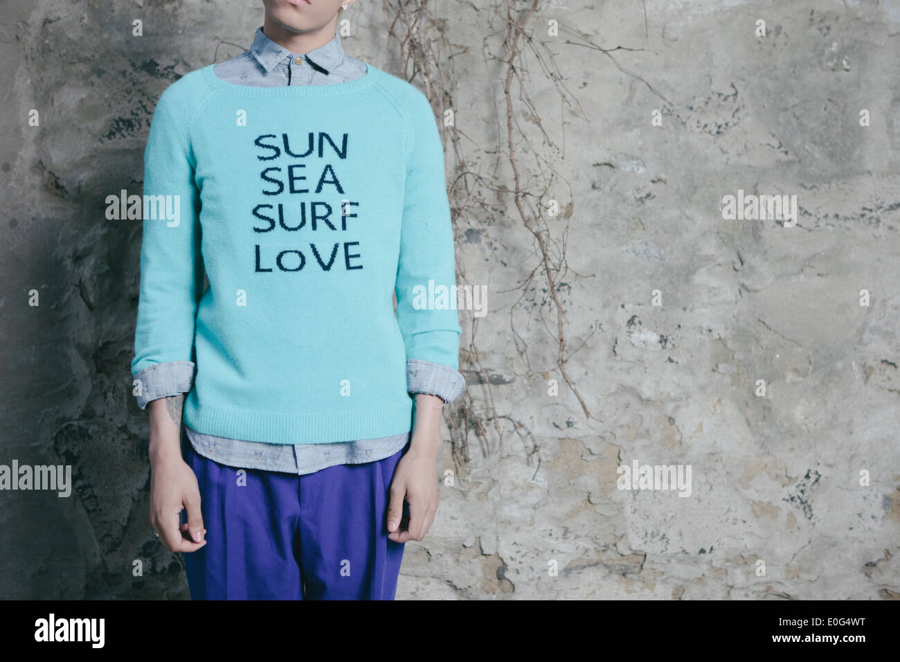 Junger Mann in einem städtischen Umfeld, träumt von Strand und wollen dorthin zu gehen, 'Sonne, Meer, Brandung, Liebe' auf dem Pullover gedruckt. Stockfoto