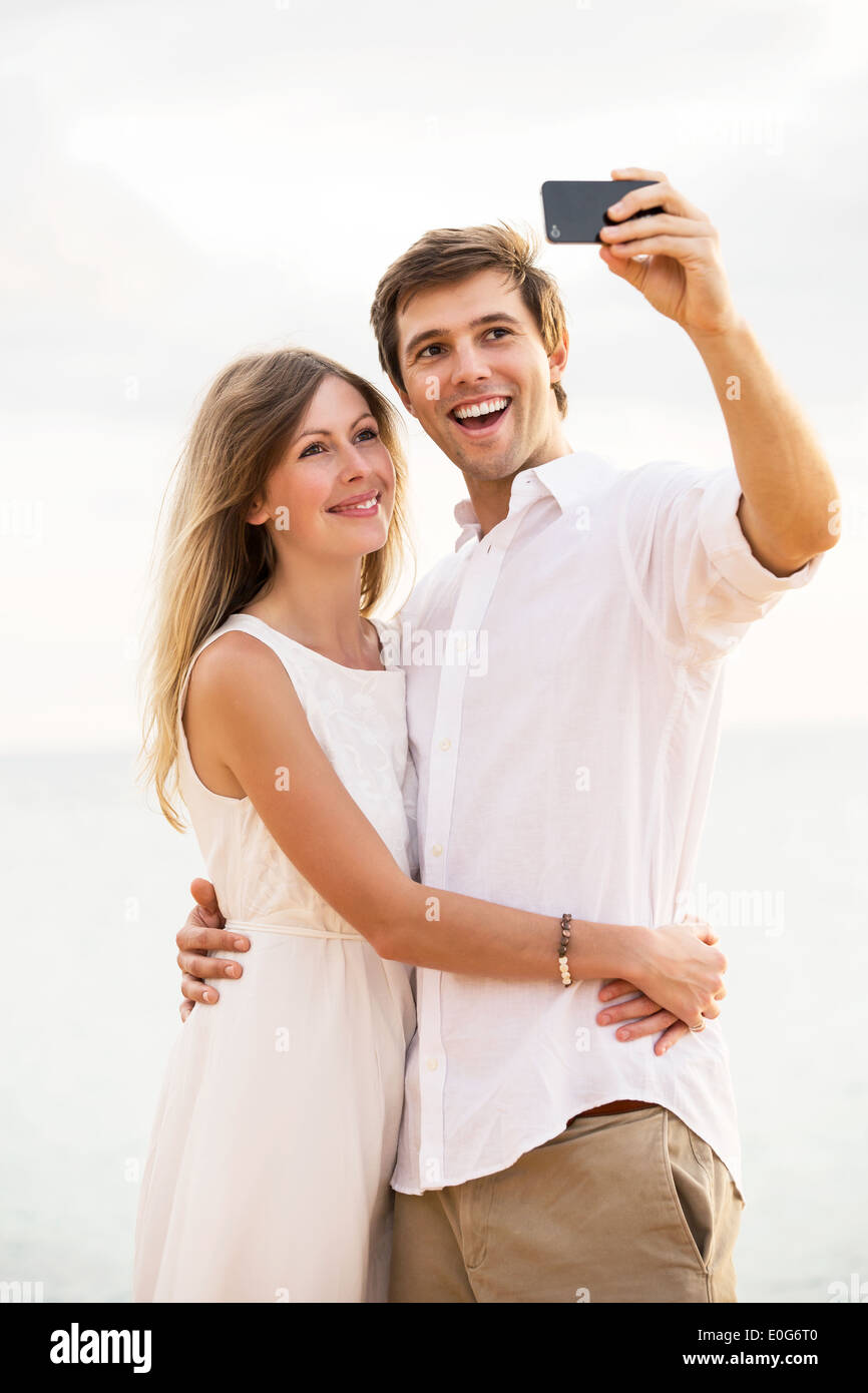 Glückliches junges Paar unter einem Selfie am Strand bei Sonnenuntergang Stockfoto
