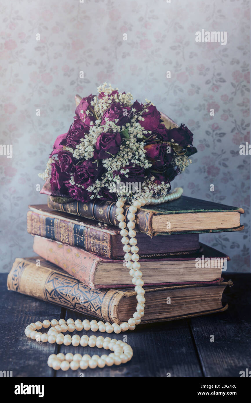 eine getrocknete rose Bouquet auf einem Stapel alter Bücher Stockfoto