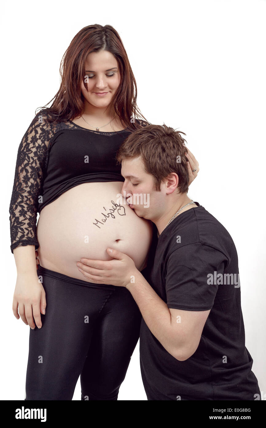glückliches Liebespaar, schwangere Frau mit ihrem Ehemann, isoliert auf weißem Hintergrund, Mann küssen Bauch Stockfoto