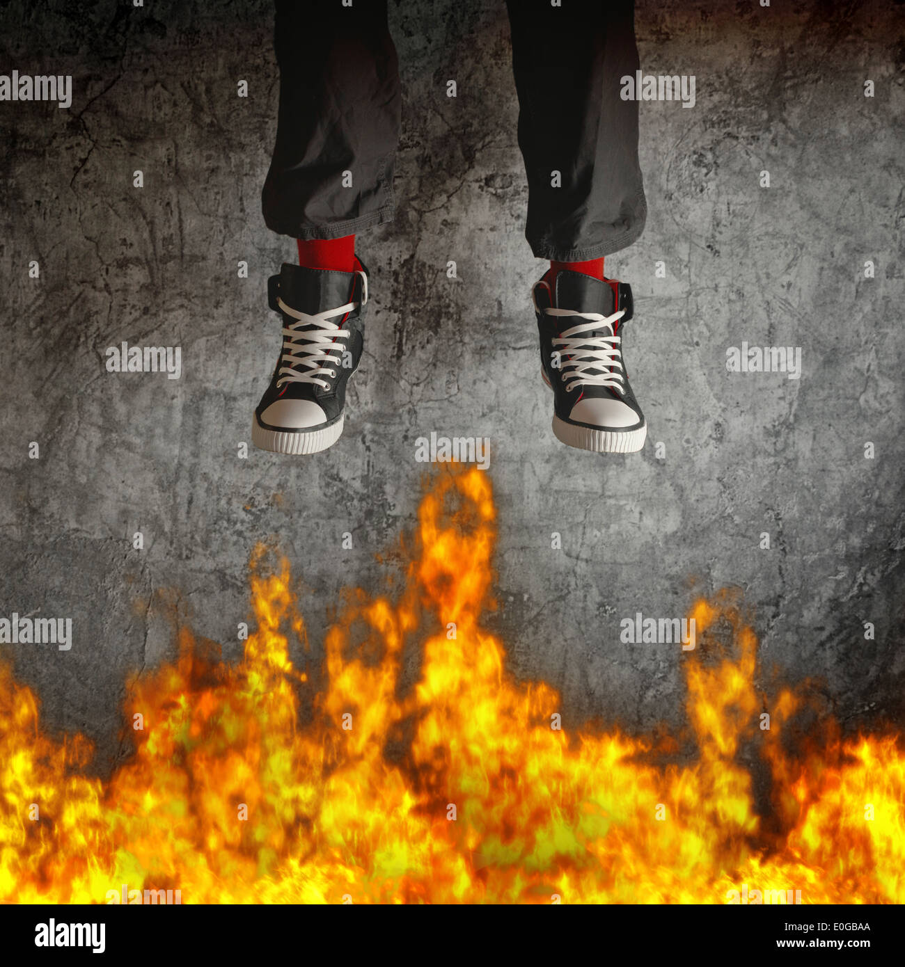Junger Mann in Turnschuhen wird über Feuer Flammen springen. Konzept der Rücksichtslosigkeit und Risiko. Stockfoto