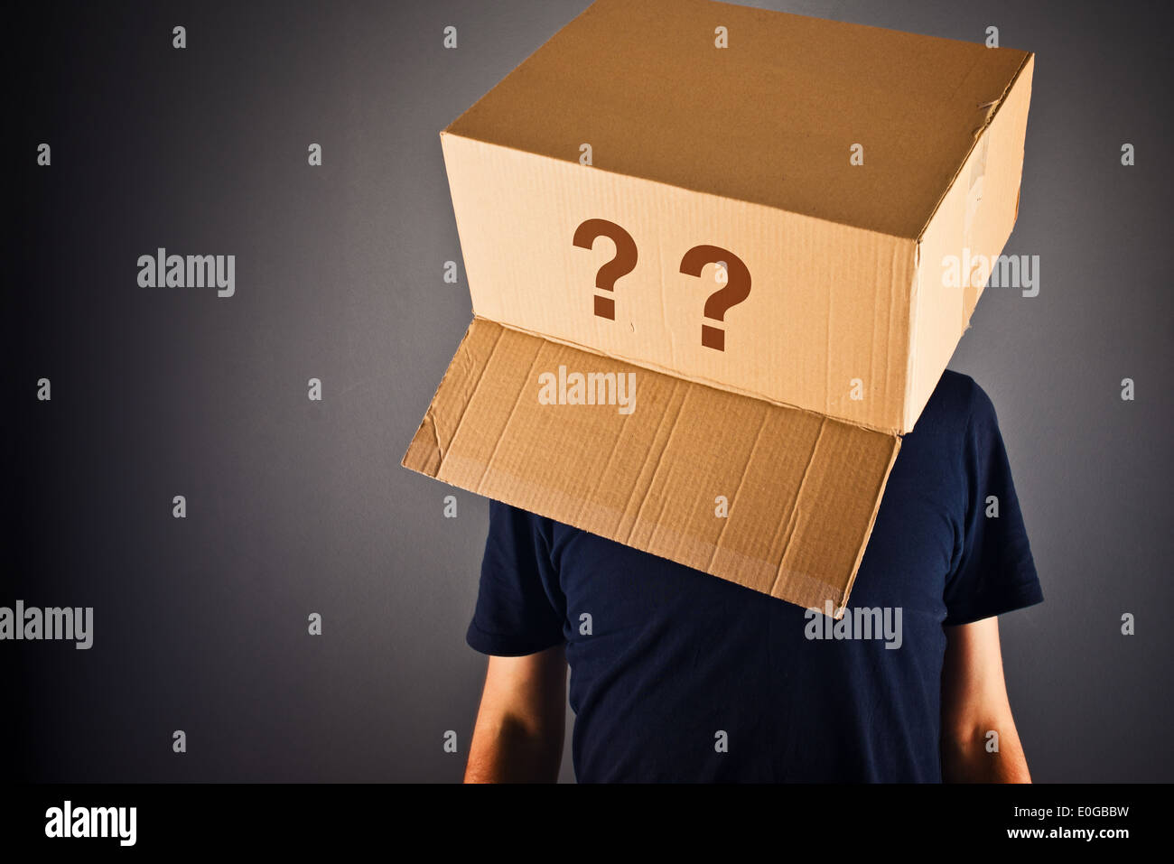 Mann mit Karton auf seinem Kopf in Frage zu stellen. Fragen ohne Antworten. Stockfoto
