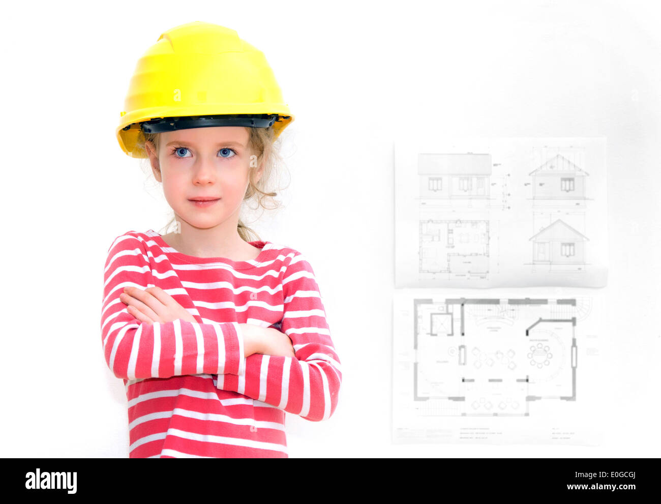 Kleines Mädchen in harten Hut Stand in der Nähe der Wand mit Hausplan. Stockfoto